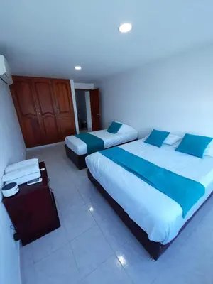 a bedroom with two beds and a suitcase in it at Apartamento en Cartagena Edificio El conquistador Sector el Laguito - By Corfeinco in Cartagena de Indias