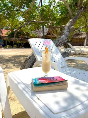 a drink sitting on a table with a book at Hotel Carey Beach Baru in Baru