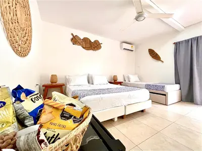 a room with two beds and a table in it at Hotel Carey Beach Baru in Baru