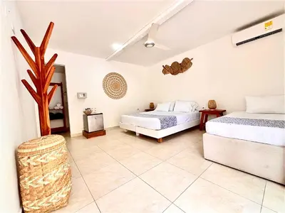 a bedroom with two beds and a tree in it at Hotel Carey Beach Baru in Baru