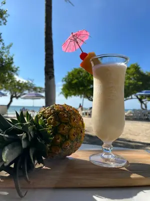 a drink in a glass next to a pineapple on a table at Hotel Carey Beach Baru in Baru