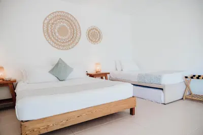 two beds in a room with white walls at Hotel Carey Beach Baru in Baru