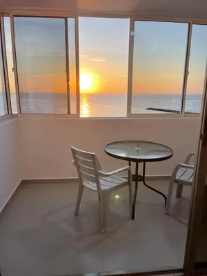 a table and chairs in front of a window with the sunset at Hermoso Apartamento, con vista al mar, en Cartagena de Indias, dos cuartos in Cartagena de Indias