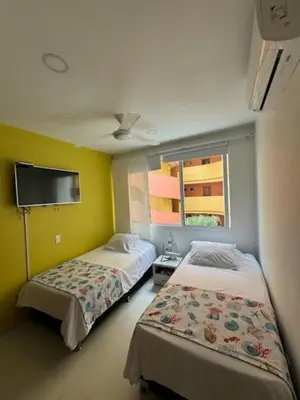 a room with two beds and a tv on the wall at Hermoso apartamento en la mejor zona de la ciudad in Cartagena de Indias