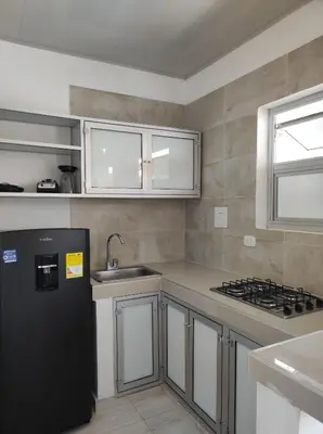 a kitchen with a black refrigerator and a sink at Apartamentos Villa Leonor in Coveñas