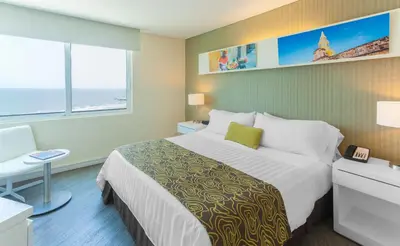 a hotel room with a large bed and a window at GHL Corales de Indias in Cartagena de Indias