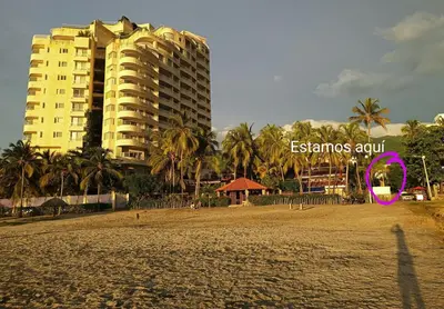 a beach with a tall building and a pink kite at Amplio dúplex con playa y mall a una cuadra in Santa Marta