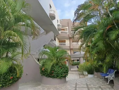 a building with palm trees in front of it at Amplio dúplex con playa y mall a una cuadra in Santa Marta