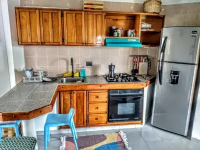 a kitchen with a stainless steel refrigerator and wooden cabinets at Amplio dúplex con playa y mall a una cuadra in Santa Marta