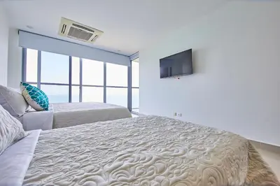 a bedroom with a large bed and a flat screen tv at Beachfront Paradise with Outstanding Sunset Views in Cartagena de Indias
