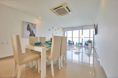 a white dining room with a table and chairs at Beachfront Paradise with Outstanding Sunset Views in Cartagena de Indias