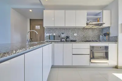 a white kitchen with white cabinets and a sink at Beachfront Paradise with Outstanding Sunset Views in Cartagena de Indias