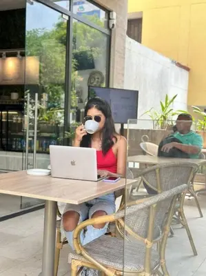 a woman sitting at a table with a cup of coffee at Gz Tower Apartamento Barranquilla in Barranquilla