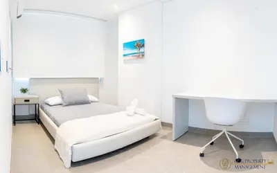 a white bedroom with a bed and a desk at Distrito 90 - Estudios y Apartamentos para vacaciones y viajes de negocio in Barranquilla
