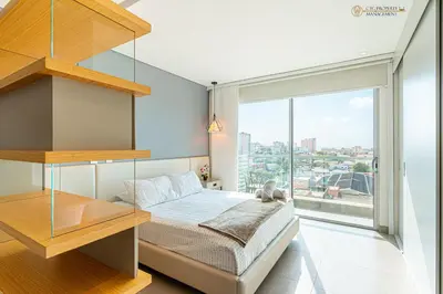 a bedroom with a bed and a large window at Distrito 90 - Estudios y Apartamentos para vacaciones y viajes de negocio in Barranquilla
