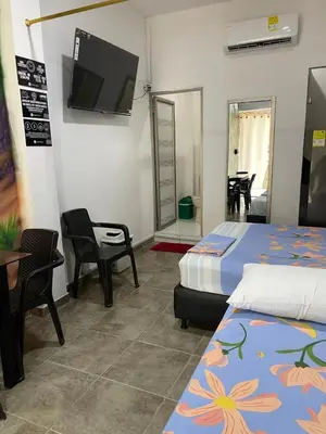 a bedroom with two beds and a flat screen tv at Cabañas Melany in Coveñas