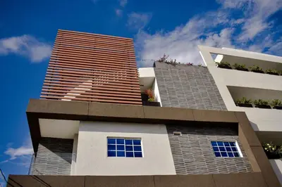 a tall white building with windows and a blue sky at Cienaguas Hotel in Ciénaga