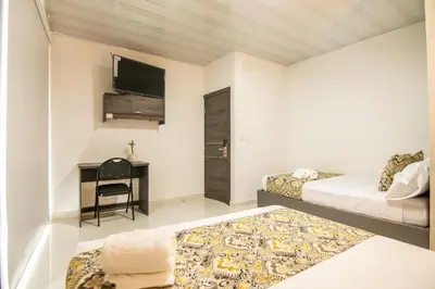 a room with two beds and a desk with a television at Cienaguas Hotel in Ciénaga