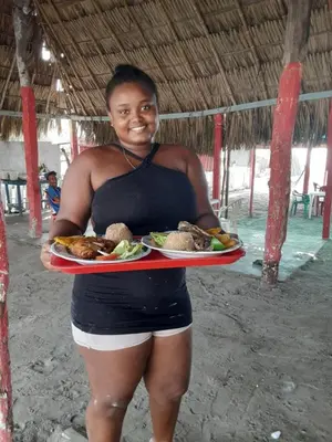 a woman holding a tray of food on the beach at Casa Playa Arreboles in Cartagena de Indias