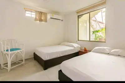 two beds in a room with a chair and a window at Casa Playa Arreboles in Cartagena de Indias