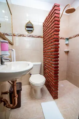 a bathroom with a white toilet and a brick wall at Scalea Di Mare Hotel in Cartagena de Indias