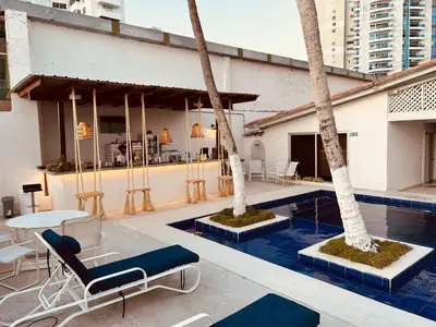 a pool with two palm trees and a table and chairs at Wala Hotel and Beach Club in Cartagena de Indias