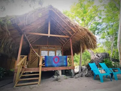 a small hut with two blue chairs and a thatched roof at Centro Ubuntu in Isla Grande