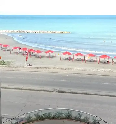 a beach with red umbrellas and the ocean at Apartamento mar in Cartagena de Indias