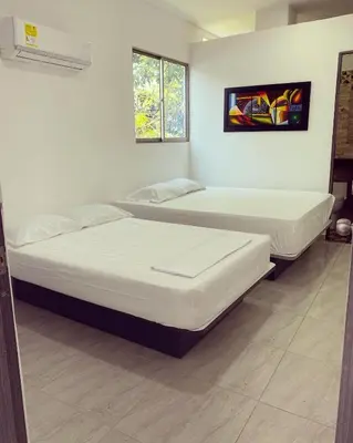 two beds in a room with white walls at Murano Hotel in Coveñas