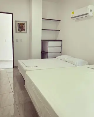 two beds in a room with white walls at Murano Hotel in Coveñas