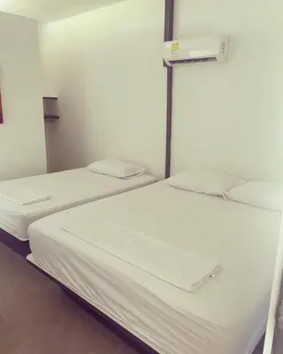 two beds in a room with white sheets and pillows at Murano Hotel in Coveñas