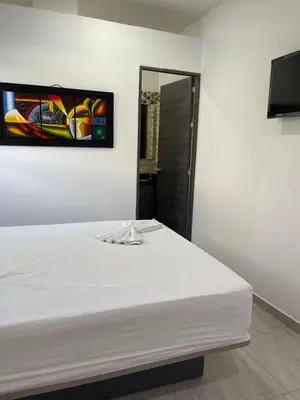 a white bed in a room with a painting on the wall at Murano Hotel in Coveñas