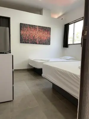 a bedroom with two beds and a painting on the wall at Murano Hotel in Coveñas