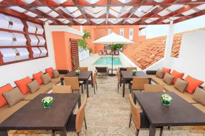 an outdoor patio with tables and chairs and a pool at Hotel Boutique Casa del Coliseo in Cartagena de Indias