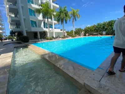 a man standing next to a swimming pool in front of a building at Playa -Boquilla -Apto en Condominio in Cartagena de Indias