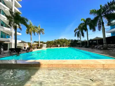 a large swimming pool with palm trees and a building at Apto- Condominio H Sonesta - Morros-salida a la playa - cerca Hotel Americas in Cartagena de Indias