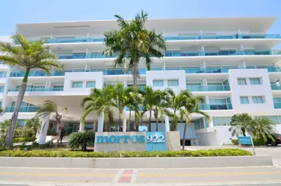 a large white building with palm trees in front of it at Cartagena Genius Morros frente al mar in Cartagena de Indias