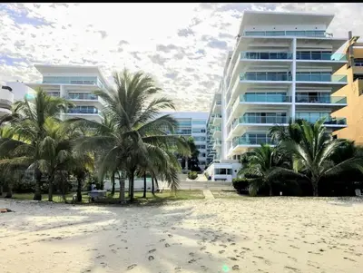 a beach with palm trees in front of a building at Cartagena Genius Morros frente al mar in Cartagena de Indias