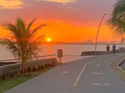 two people walking down a sidewalk near the water at sunset at 19TH FLOOR LUXURY APARTMENT BAY VIEW CARTAGENA in Cartagena de Indias