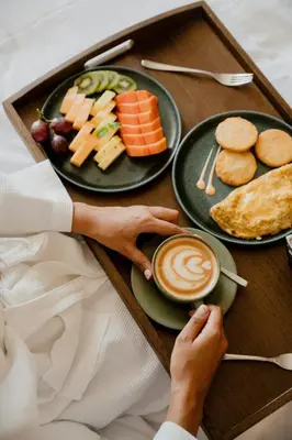a woman holding a cup of coffee next to a tray of food at Barranquilla Marriott Hotel in Barranquilla