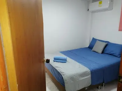 a small bedroom with a bed with blue sheets at Casa La Fe in Cartagena de Indias