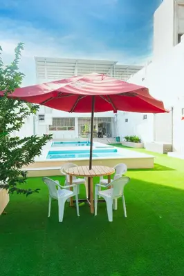 a table and chairs with a red umbrella on the grass at ZABDI COVEÑAS in Coveñas