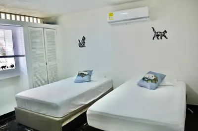 two beds in a room with white walls at Casa del Gato in Cartagena de Indias