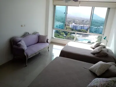 a bedroom with two beds and a couch and a window at Costa Azul Suite 804 in Santa Marta