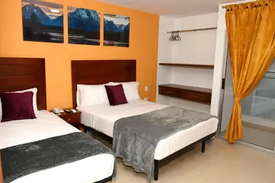 two beds in a room with orange walls at Hotel Kai Soledad Atlántico in Soledad