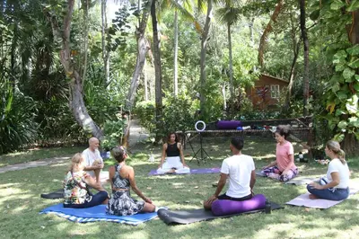 a group of people sitting in the grass doing yoga at Hostal Campomar in Santa Veronica