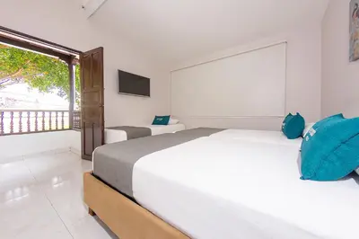 a white bedroom with two beds and a window at Ayenda Isla de Manga in Cartagena de Indias