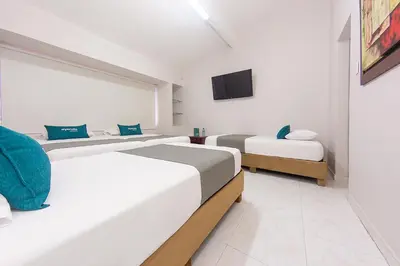 two beds in a white room with a tv at Ayenda Isla de Manga in Cartagena de Indias