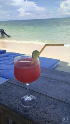 a drink sitting on a table near the beach at Hostal azul beach isla baru in Playa Blanca