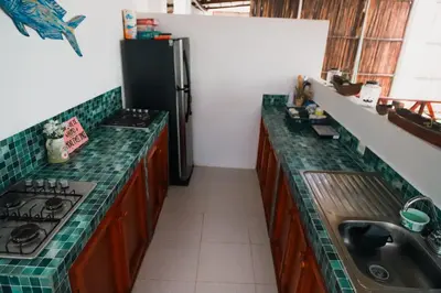 a kitchen with green counter tops and a refrigerator at Hostal Casa en la Ciénaga Rincon del Mar in Rincón